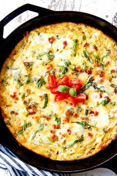 an omelet with tomatoes and basil in a cast iron skillet on a table