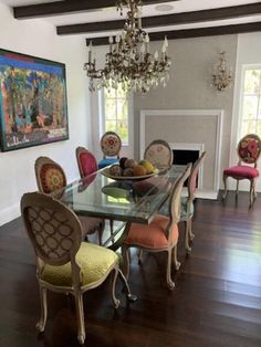 a dining room table with colorful chairs and a chandelier hanging from the ceiling