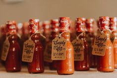 several bottles of hot sauce are lined up on a table with tags attached to them