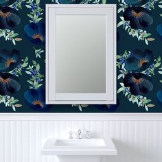 a bathroom sink sitting under a mirror next to a wall mounted vanity with blue flowers on it