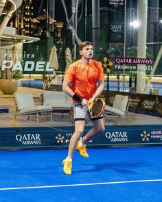 a young man holding a tennis racquet on top of a blue tennis court