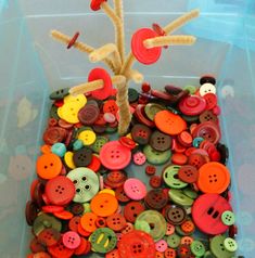 a plastic container filled with lots of different colored buttons and pins on top of each other