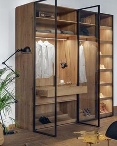 an open closet with clothes hanging on the shelves, and a chair next to it