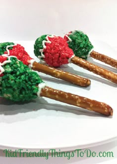 four pretzels with green and red toppings are on a white platter