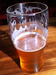 a glass filled with liquid sitting on top of a wooden table