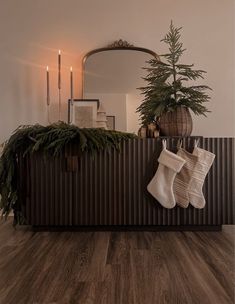 stockings hanging on the wall next to a christmas tree and fireplace mantel with candles