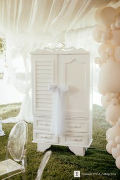 a white armoire with balloons hanging from it's sides and a bow on the door