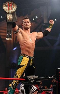 a man standing in the middle of a wrestling ring holding up a large metal object