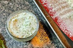 a glass bowl filled with food sitting on top of a counter next to a spatula