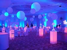 a banquet hall decorated with white and blue lights, round balloons and bar stools