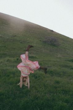 a woman in a pink dress standing on her back legs while holding a frisbee