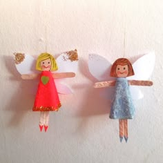 two paper angel ornaments hanging on a wall next to each other in the shape of children's angels