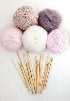 several skeins of yarn and knitting needles on a white surface