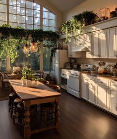 a kitchen filled with lots of white appliances and wooden table surrounded by potted plants