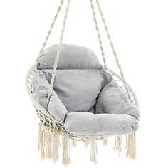 a grey hanging chair with rope and tassels on the bottom, in front of a white background