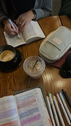 a person sitting at a table with an open book and some writing utensils