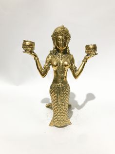 a gold colored figurine holding two cups in each hand and an empty bowl in the other