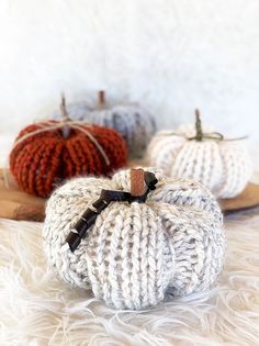 three knitted pumpkins sitting next to each other on a white furnishing