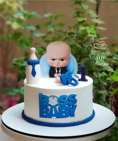 a baby is sitting on top of a boss's baby cake with blue letters