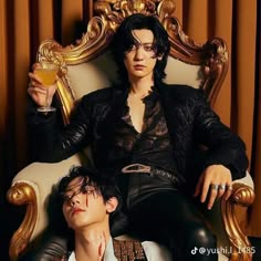 two young men sitting on top of a golden chair holding drinks in their hands and posing for the camera