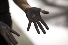 a person's hands with black paint on them