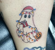 a tattoo with a ghost wearing a santa hat and holding a candy cane on it's leg