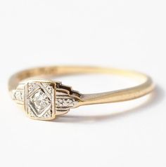 a gold and diamond ring sitting on top of a white surface