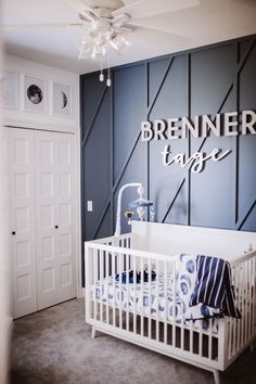 a baby's room with a white crib in the middle and a blue wall behind it