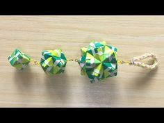 three origami balls tied together on a wooden table, with the string attached to them