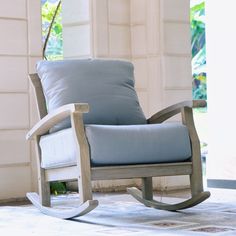 a rocking chair with blue cushions in front of an open door and window behind it