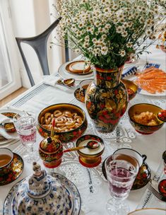 a table is set with dishes, cups and vases filled with flowers on it