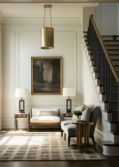 a living room filled with furniture next to a stair case and a painting on the wall