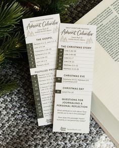 two bookmarks sitting on top of a pile of books next to a christmas tree