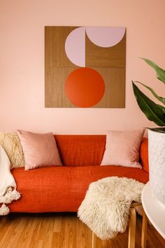 a living room with an orange couch and large painting