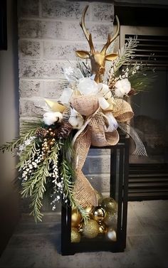 a deer head is on top of a lantern decorated with christmas balls and greenery