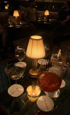 a table topped with wine glasses and plates next to a lamp on top of a table