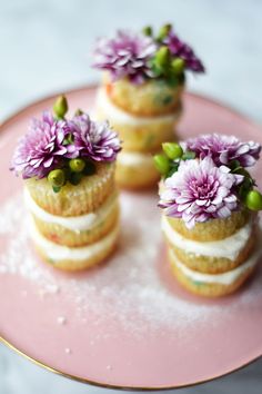 three small cakes with flowers on them sitting on a pink plate