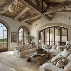 a living room filled with lots of furniture next to large arched windows on the wall