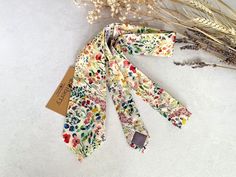 three ties with flowers on them sitting next to some dried grass and dry stalks in the background