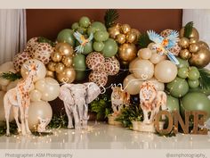 some giraffes and other animals are on display in front of many balloons