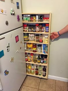 someone is trying to open the bottom shelf of a refrigerator with magnets on it