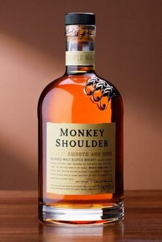 a bottle of monkey shoulderr on a table with a brown wall in the background