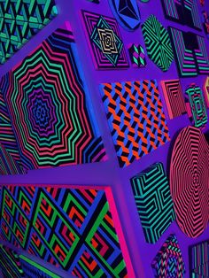 an array of different colored designs on a purple wall with blue and red lights in the background