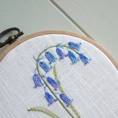 a close up of a cross stitch on a wooden hoop with blue flowers in it