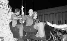 an old black and white photo of three people riding on a sleigh in front of a crowd