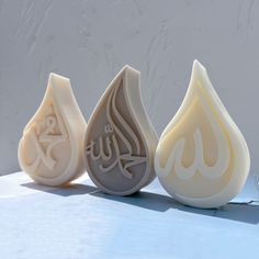 three soaps with arabic writing on them sitting in front of a white wall,