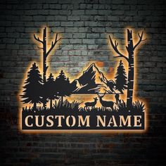 the custom name sign is lit up in front of a brick wall with trees and mountains