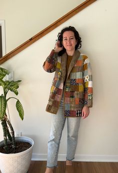 a woman standing next to a potted plant talking on a cell phone