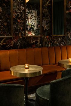 two round tables with candles on them in front of an orange couch and green chairs