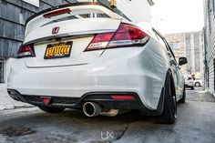 the rear end of a white car parked in front of a building